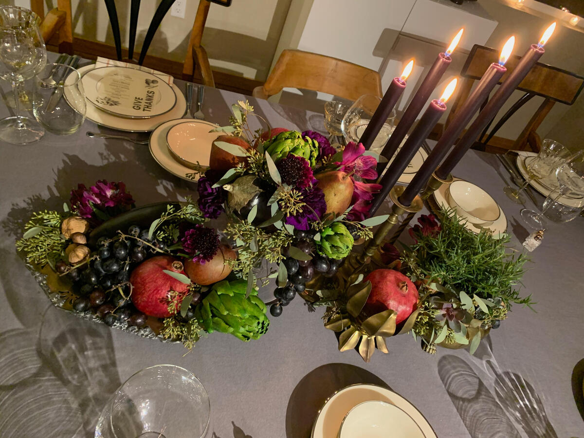 Antique mixed-metal trays piled with fruit and florals create a table of gothic abundance, contrasted with simple place settings.